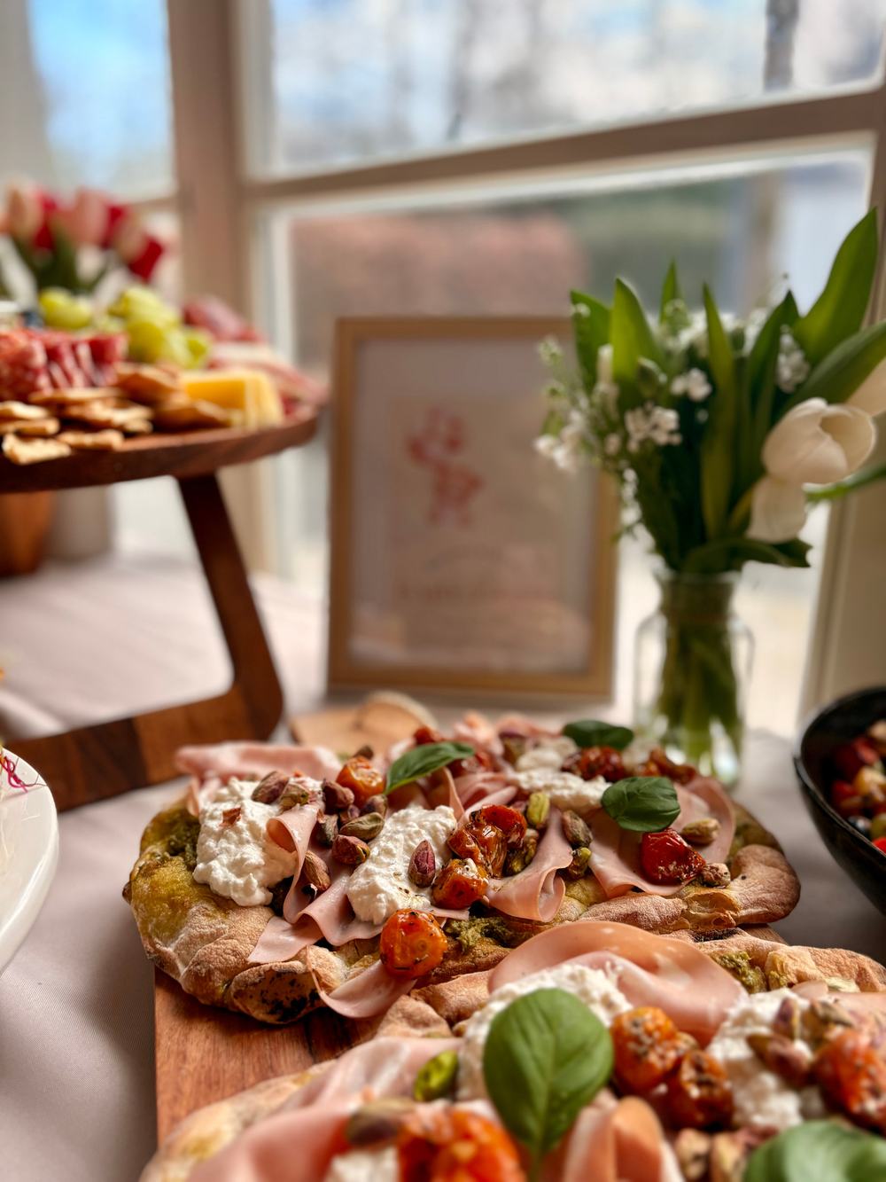 Pinsas garnies sur planche en bois près d'une fenêtre, avec un bouquet blanc