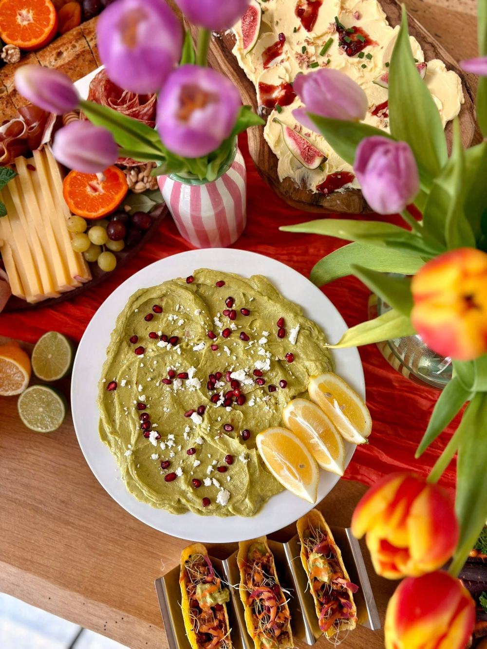 Buffet coloré vu du dessus : tulipes, avocado board, tacos, planche de fromages et agrumes